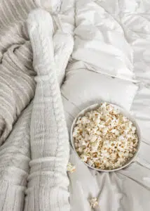 Person eating popcorn in bed. Image for How to Design a Solid Multiple Choice Assessment.