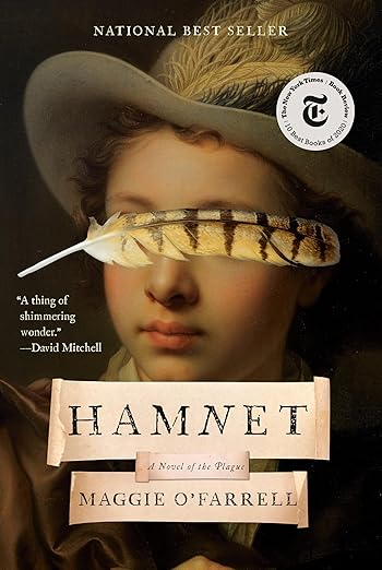 Book cover of “Hamnet” by Maggie O’Farrell. The artwork shows a classical portrait of a young boy, partially obscured by a striped feather placed horizontally across his eyes. The title appears on torn-paper labels at the bottom, and a New York Times Book Review badge is displayed in the upper right.