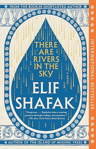 Book cover of “There Are Rivers in the Sky” by Elif Shafak. The design features a large blue teardrop shape filled with gold vertical lines resembling falling rain. The background is cream with intricate blue decorative borders. A vertical orange band on the right reads “International Bestseller.”